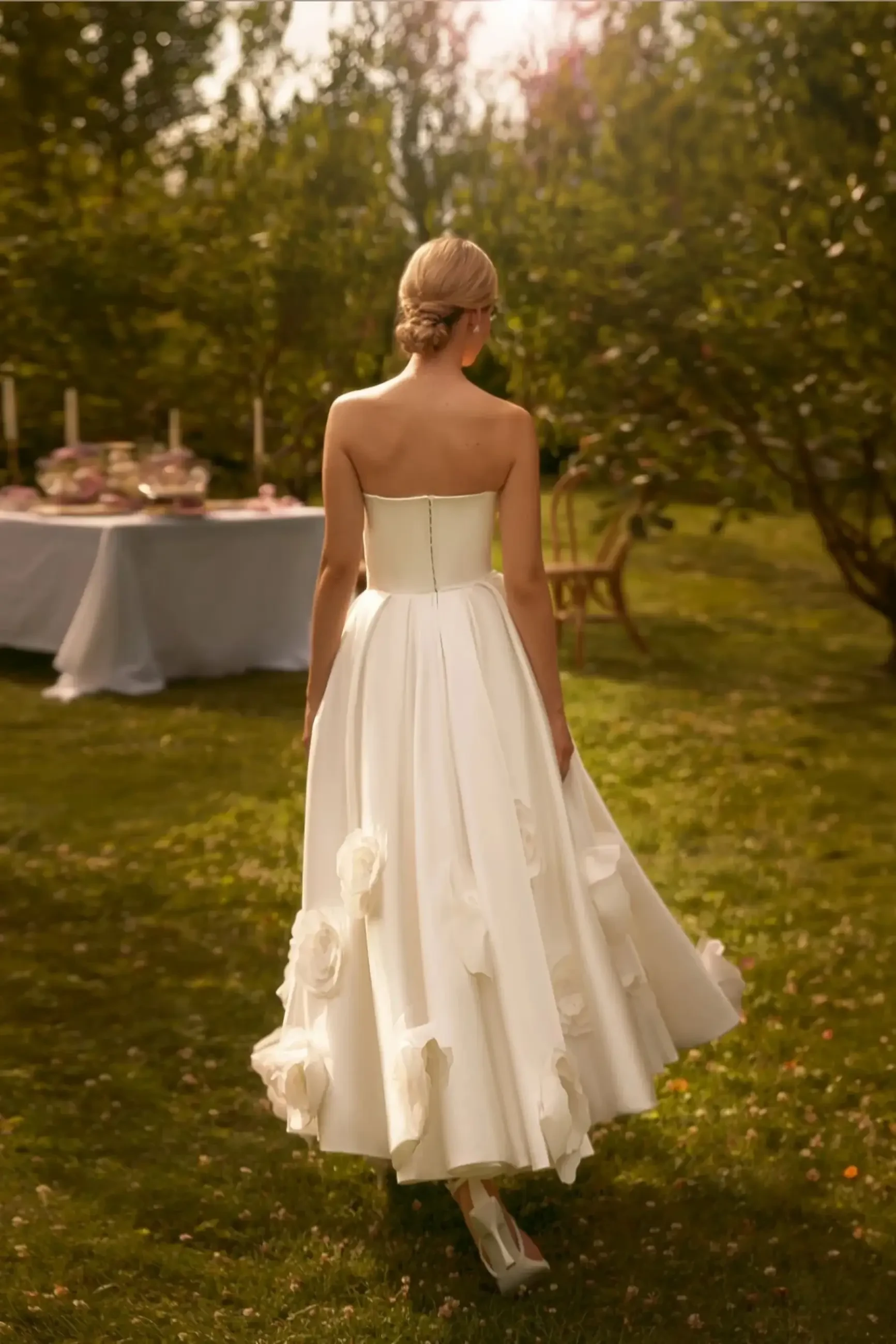 Model is wearing a satin A-line wedding gown with diagonal pleating on the bodice and oversized 3D floral accents on the full skirt.