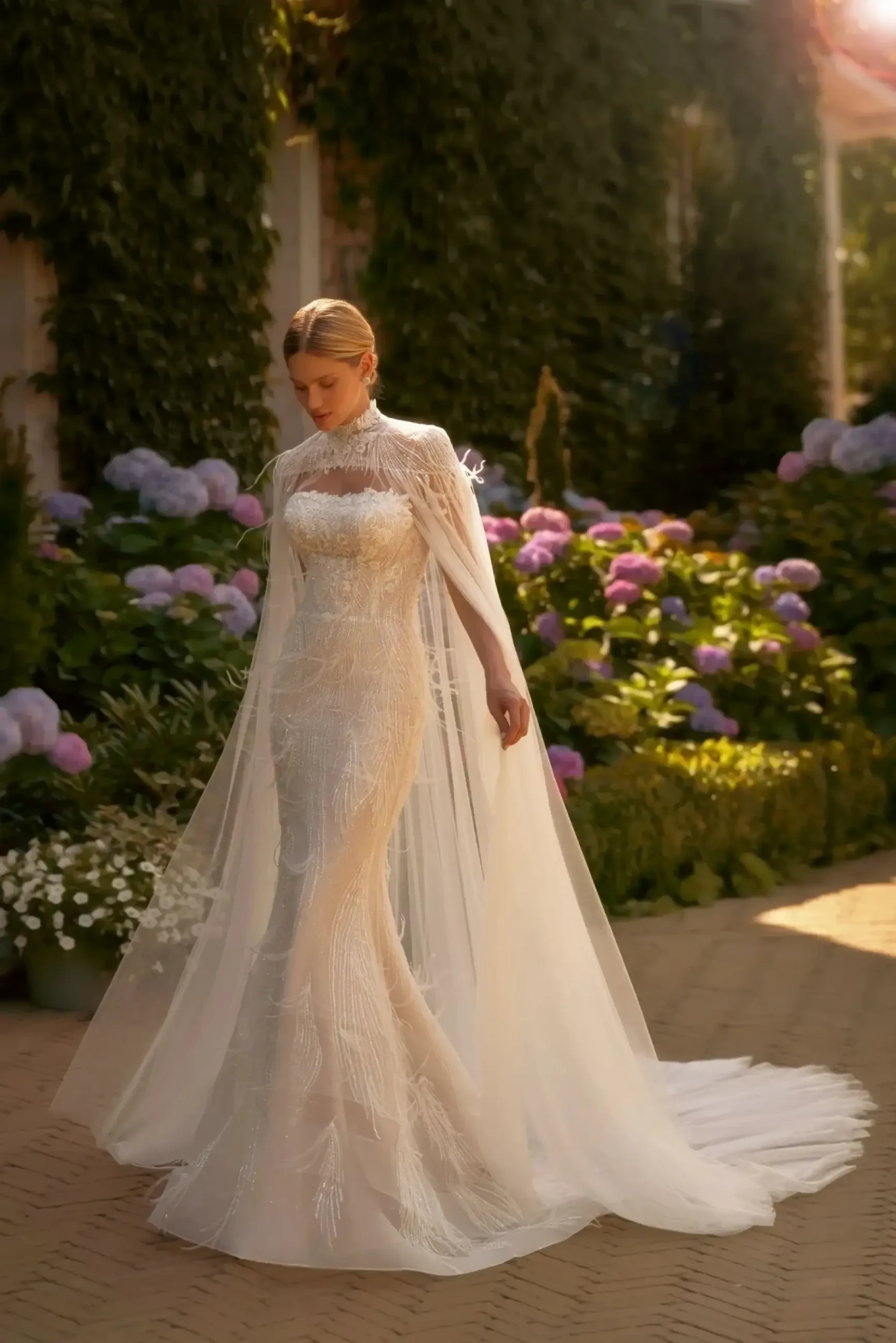 model is wearing a strapless fit and flare wedding dress with a detachable cape