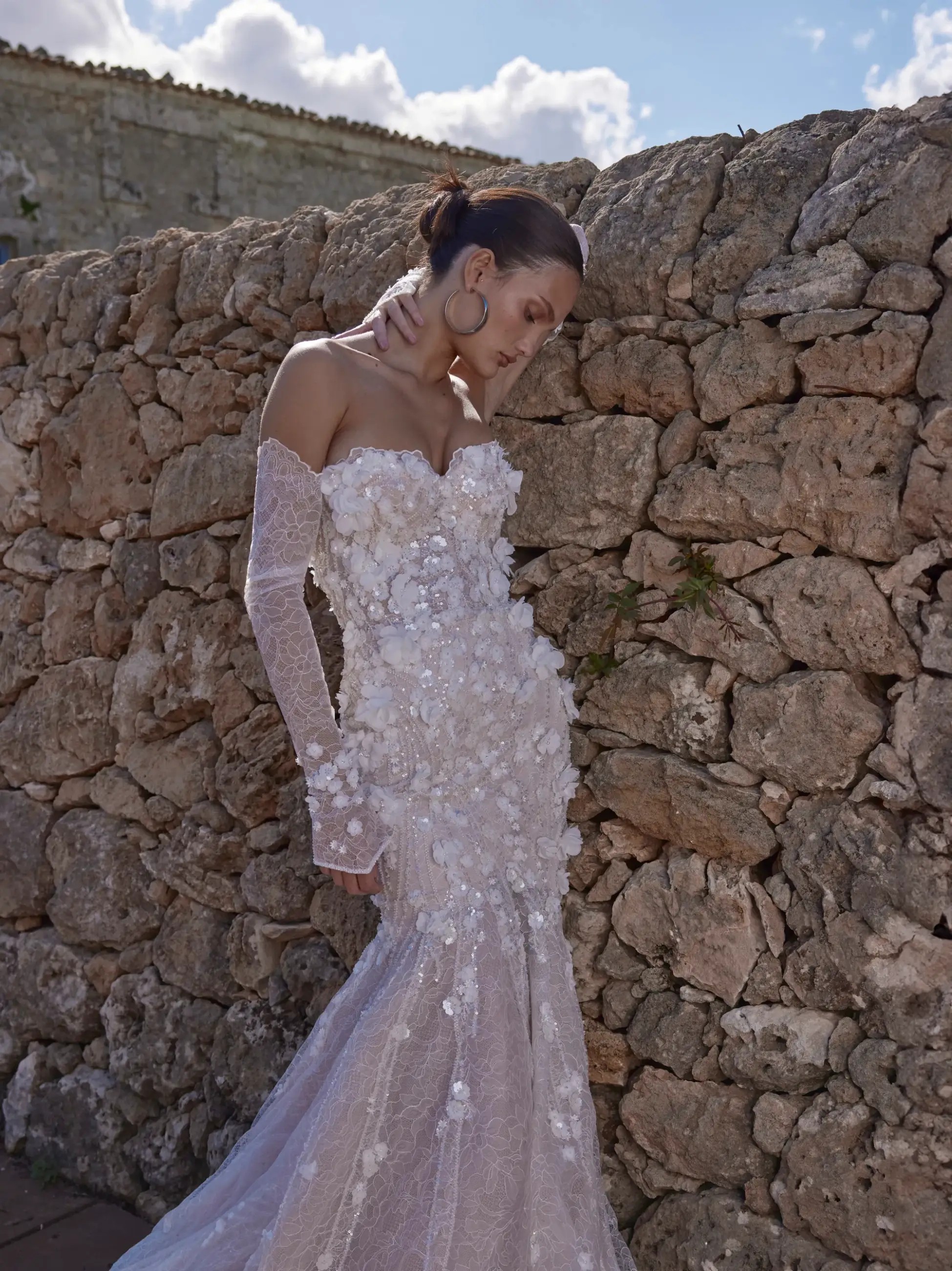 Model is wearing a wedding dress with a sweetheart neckline and intricate floral vines and lace
