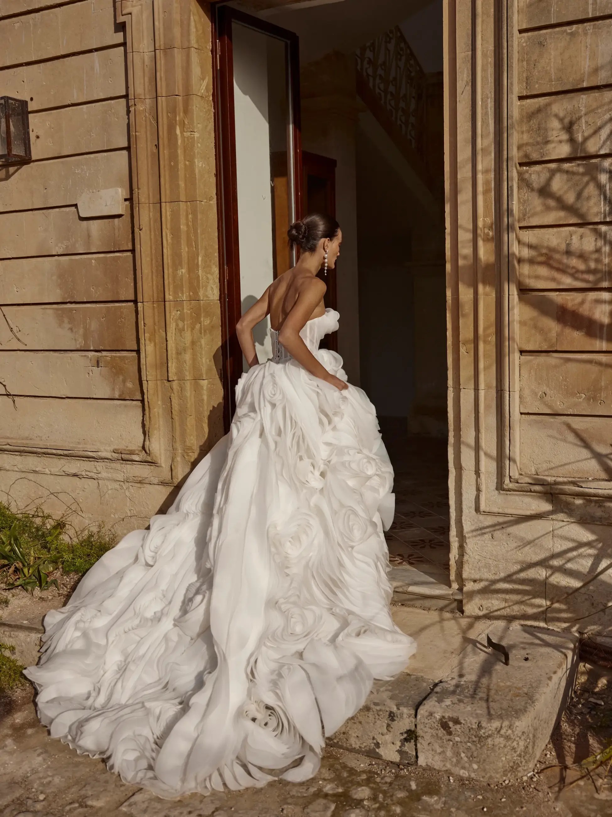Model is wearing an off the shoulder organza wedding dress and a skirt with oversized roses