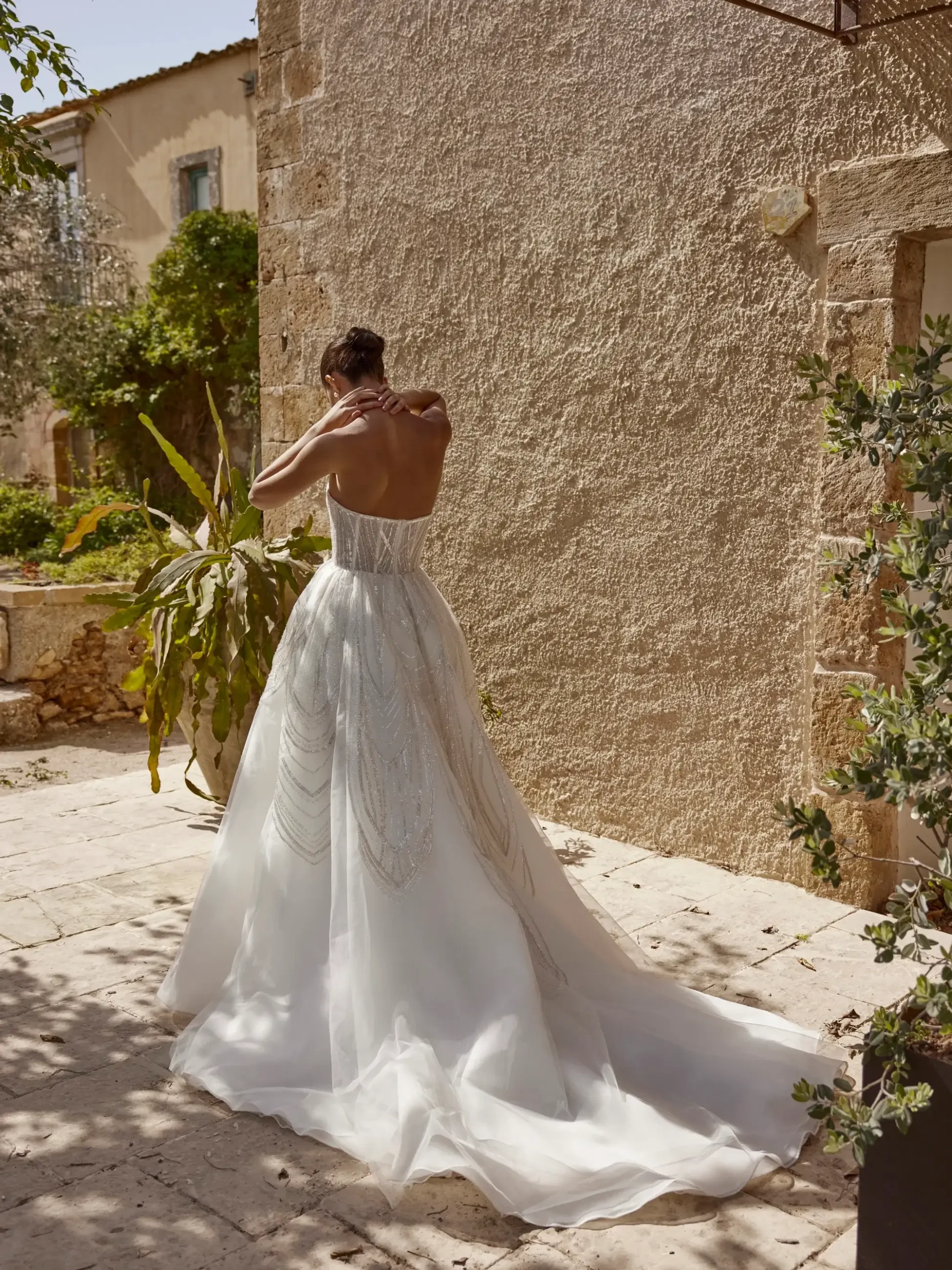 model is wearing a strapless wedding dress with a detachable cape