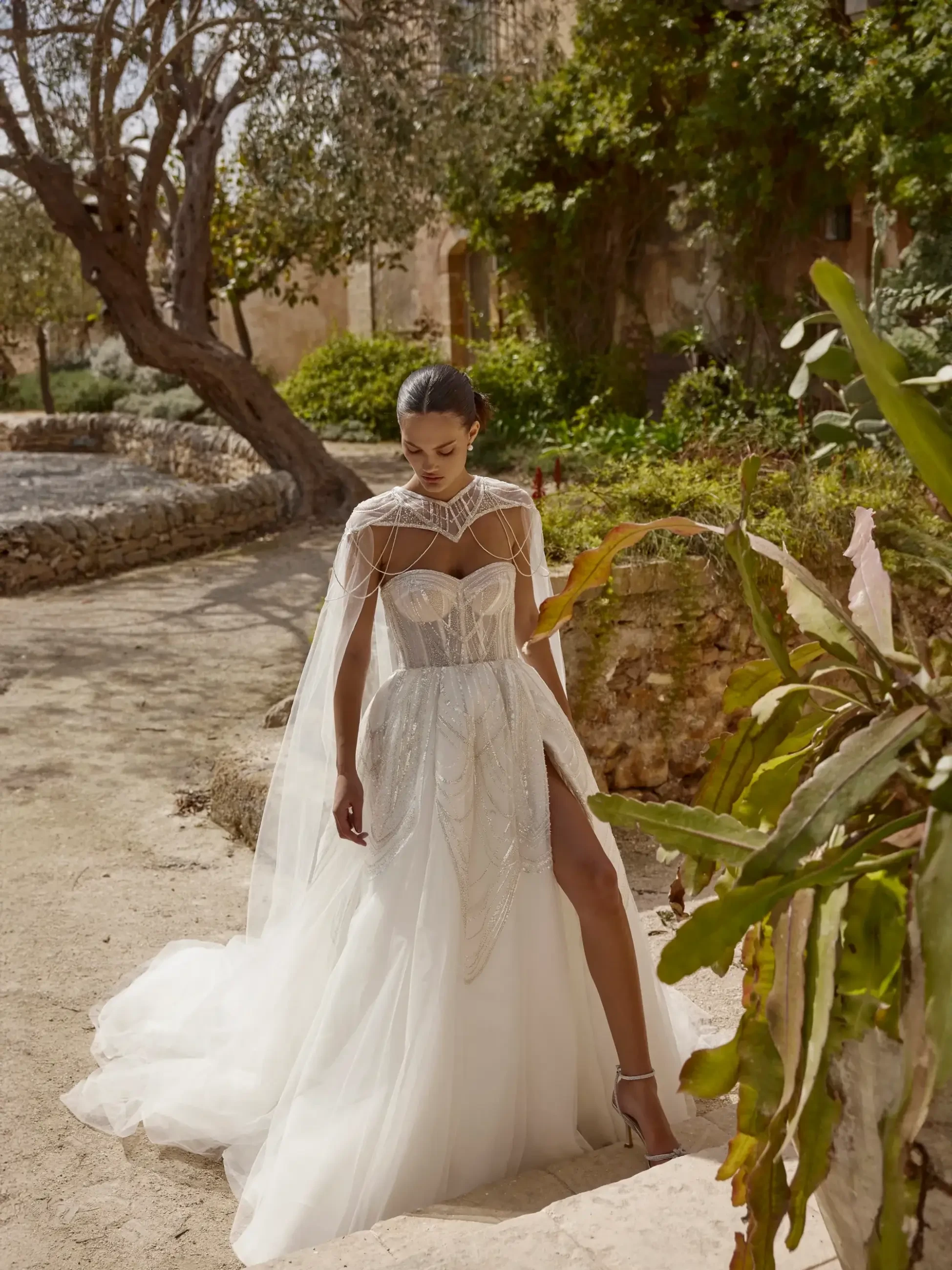 model is wearing a strapless wedding dress with a detachable cape