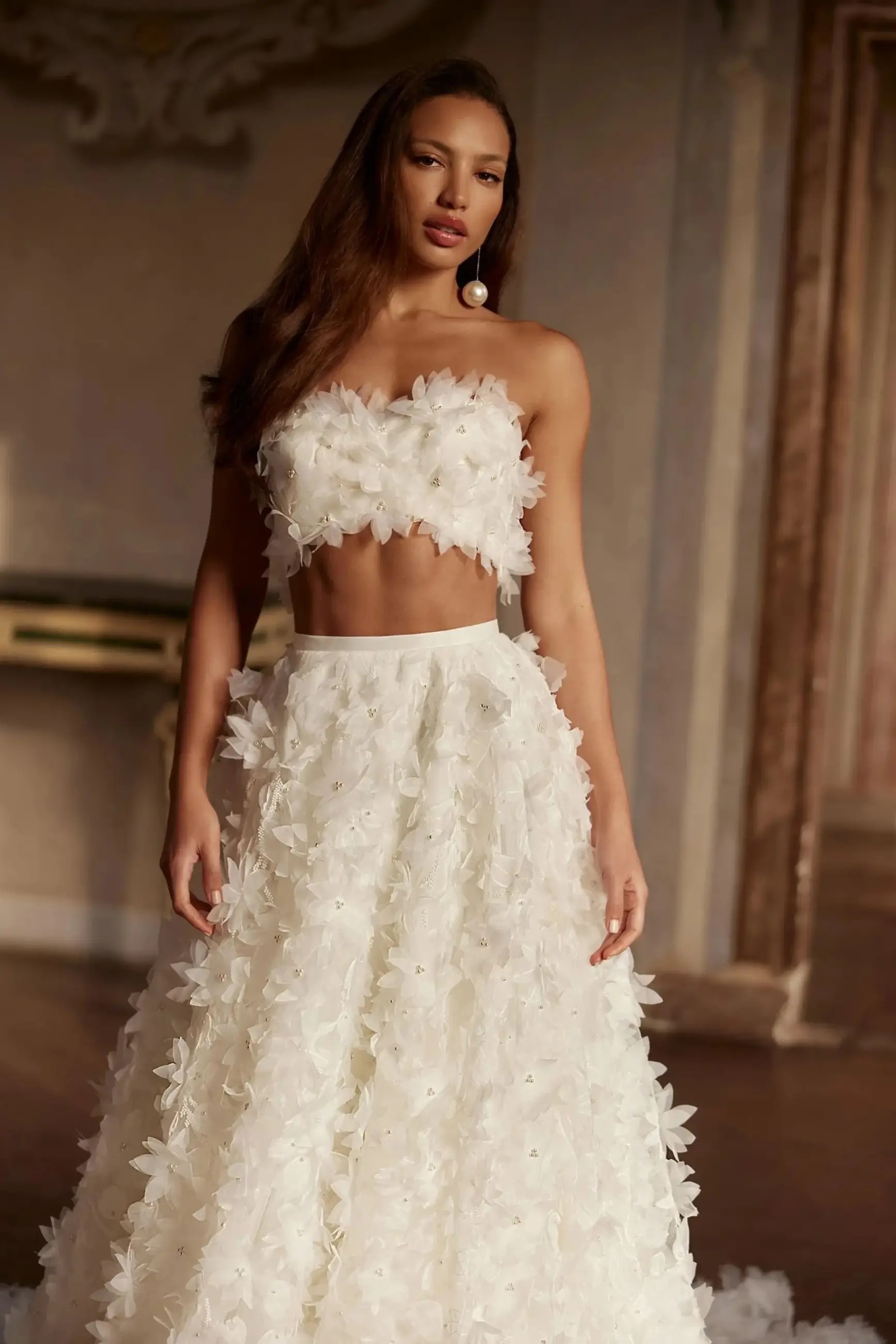 Model is wearing a floral bridal gown with a puffy skirt and cathedral style train