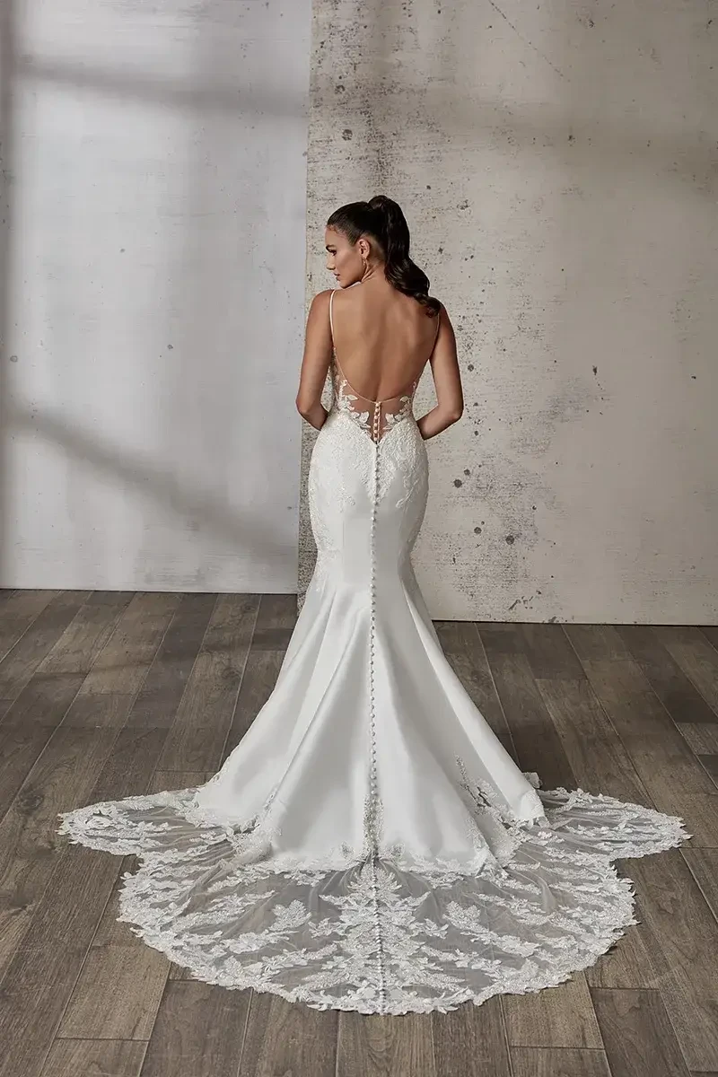 model is wearing an open back spaghetti strap wedding gown