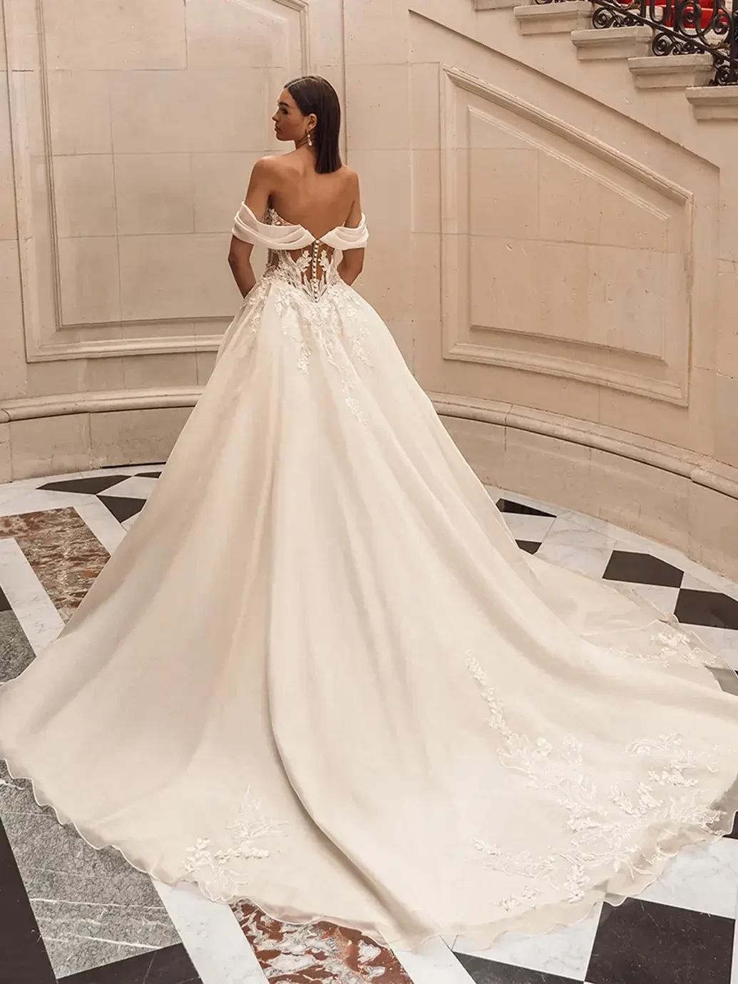Model is wearing an off the shoulder ball gown wedding dress with 3D mikado leaf details and organza floral embroidery