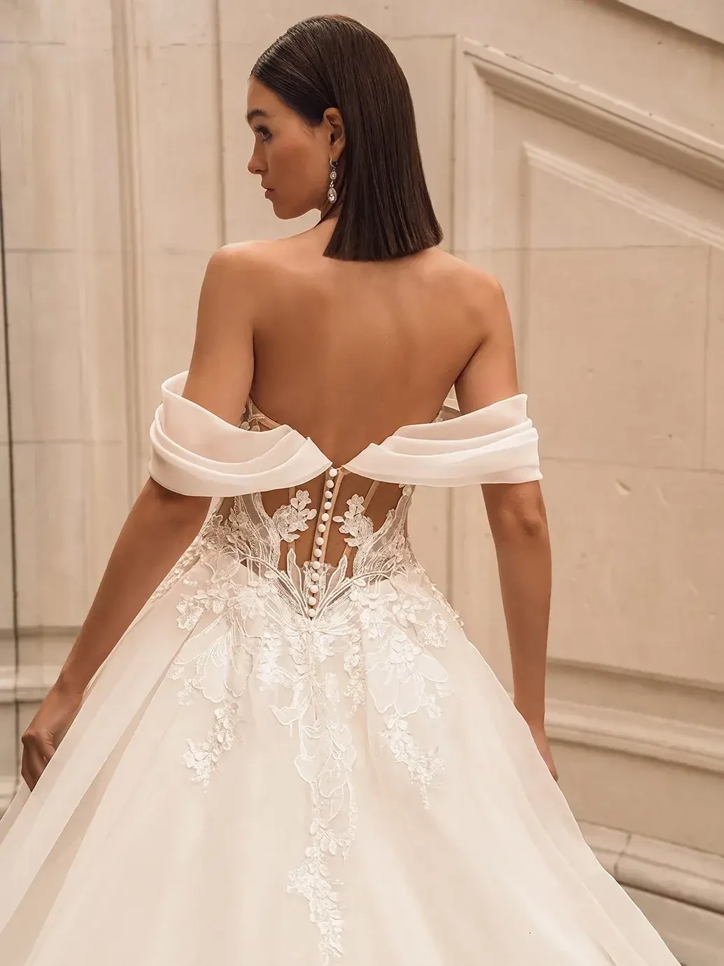 Model is wearing a fuchsia ball gown with organza floral embroidered lace, 3D Mikado leaf details, a deep sweetheart neckline, detachable off-the-shoulder straps, and a hidden high slit.