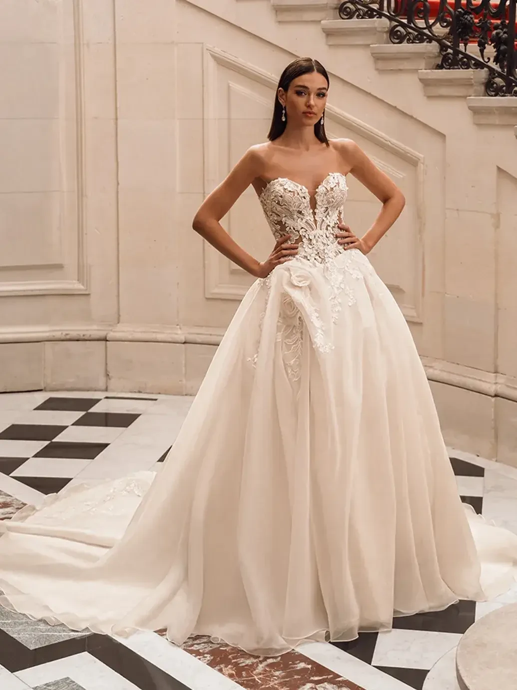 Model is wearing an off the shoulder ball gown wedding dress with 3D mikado leaf details and organza floral embroidery