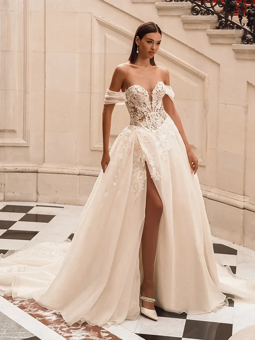 Model is wearing a fuchsia ball gown with organza floral embroidered lace, 3D Mikado leaf details, a deep sweetheart neckline, detachable off-the-shoulder straps, and a hidden high slit.