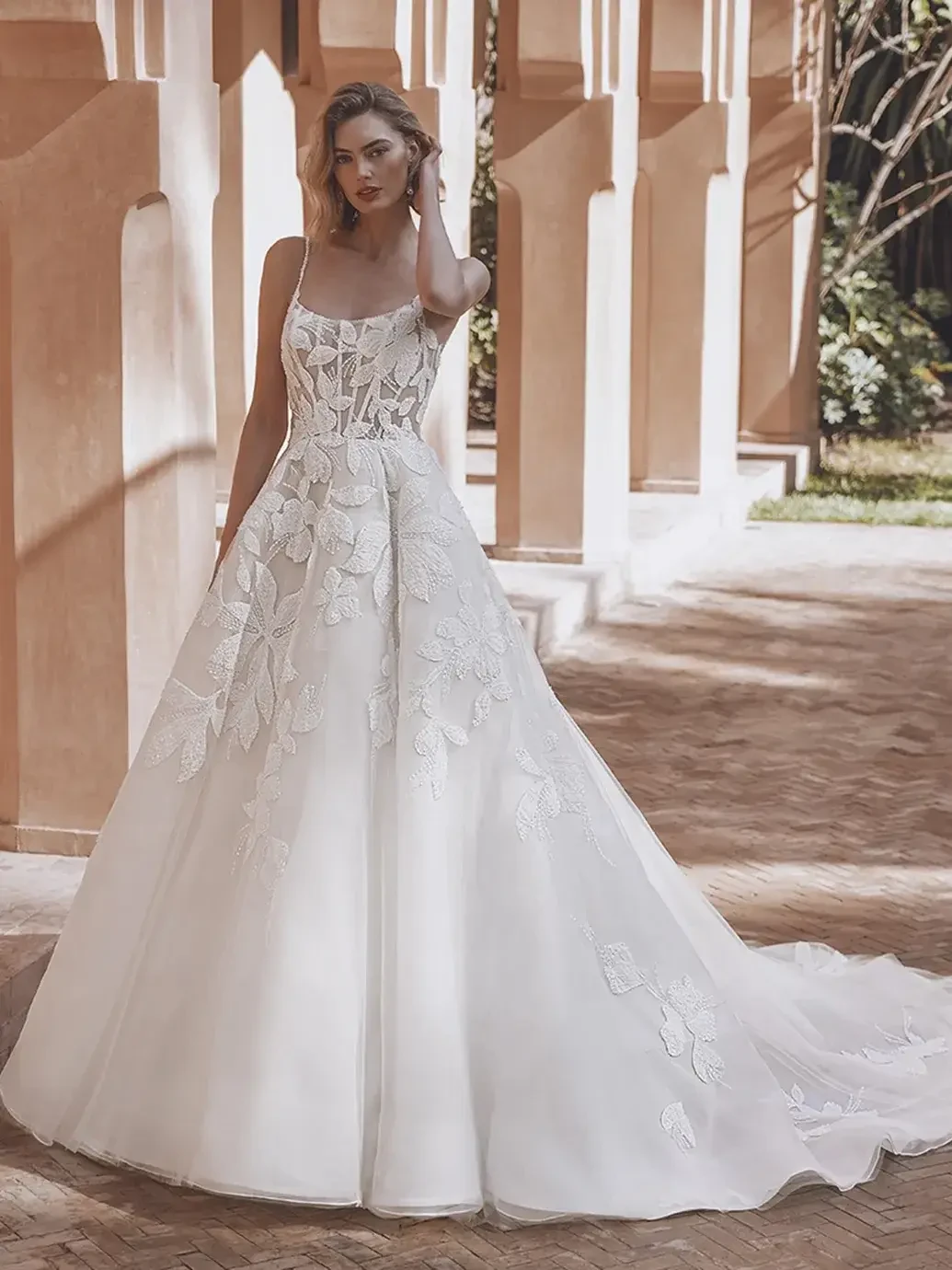 Model is wearing a sleeveless a-line wedding dress with an illusion corset bodice and 3D chiffon embroidered appliques 