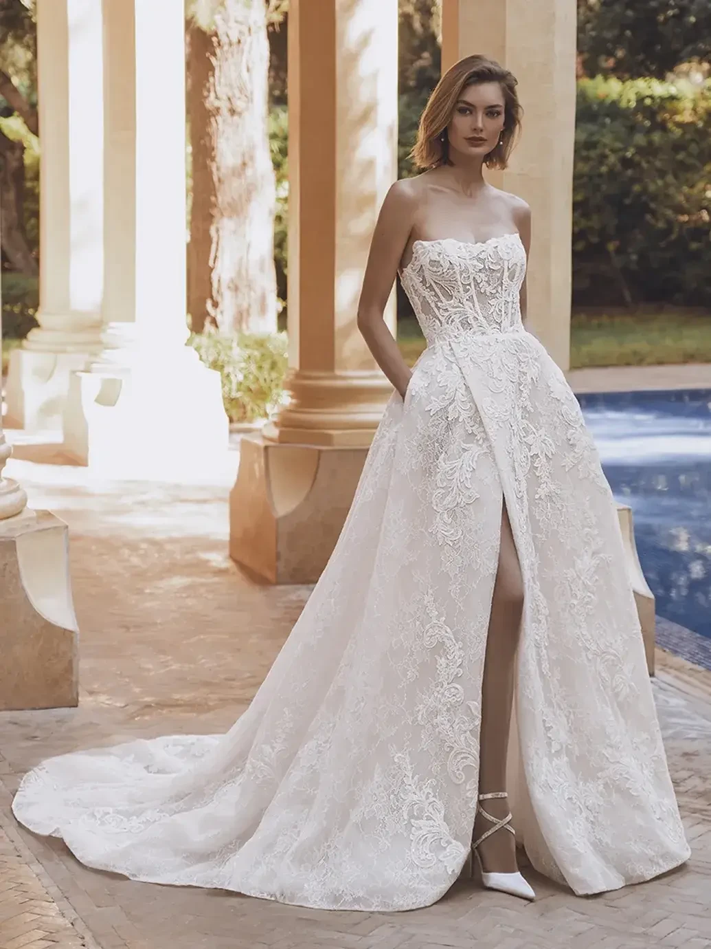 Model is wearing a luxurious ball gown with sequin corded floral lace, off-the-shoulder long sleeves, and a pleated skirt slit.